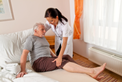 caregiver helping an elderly man in bed